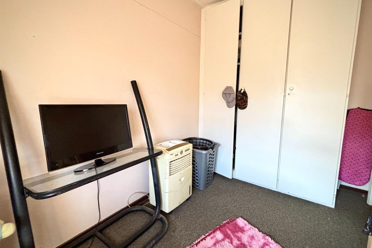 A bedroom featuring a built-in wardrobe with white doors and carpeted flooring.