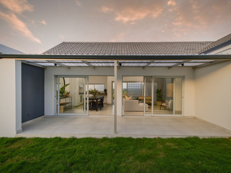 A modern covered patio featuring tiled flooring, metal support posts, and large sliding glass doors providing seamless access to the interior living spaces.