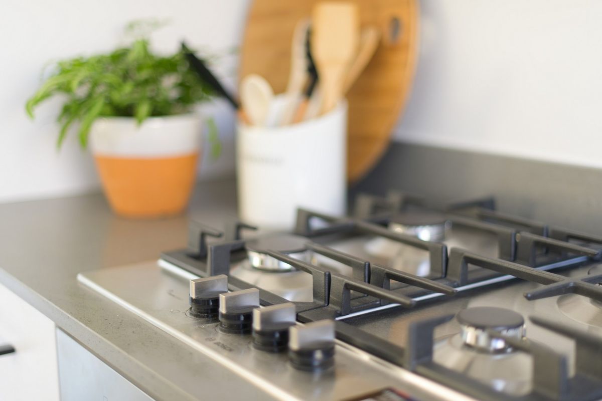 Close-up view of a modern stainless steel gas cooktop set into a stone countertop in a clean kitchen environment.