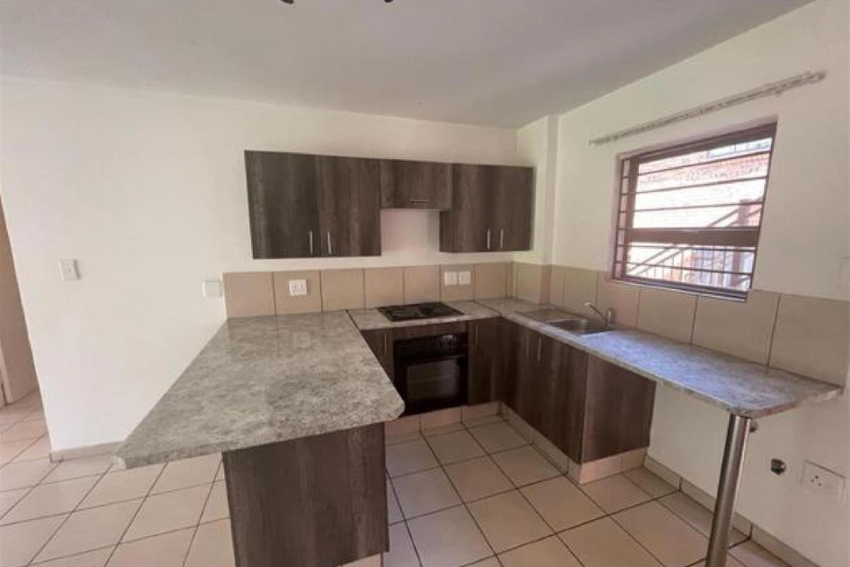 A functional kitchen featuring dark wood-look cabinetry, stone-patterned countertops, a built-in oven and hob, and tiled flooring.