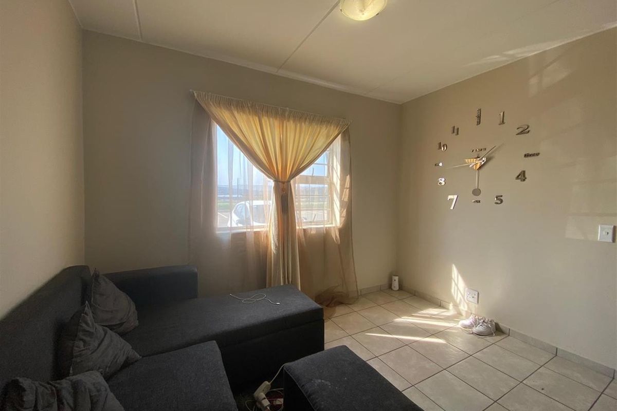 A living room featuring tiled flooring, a central ceiling light, and a window with natural light exposure.