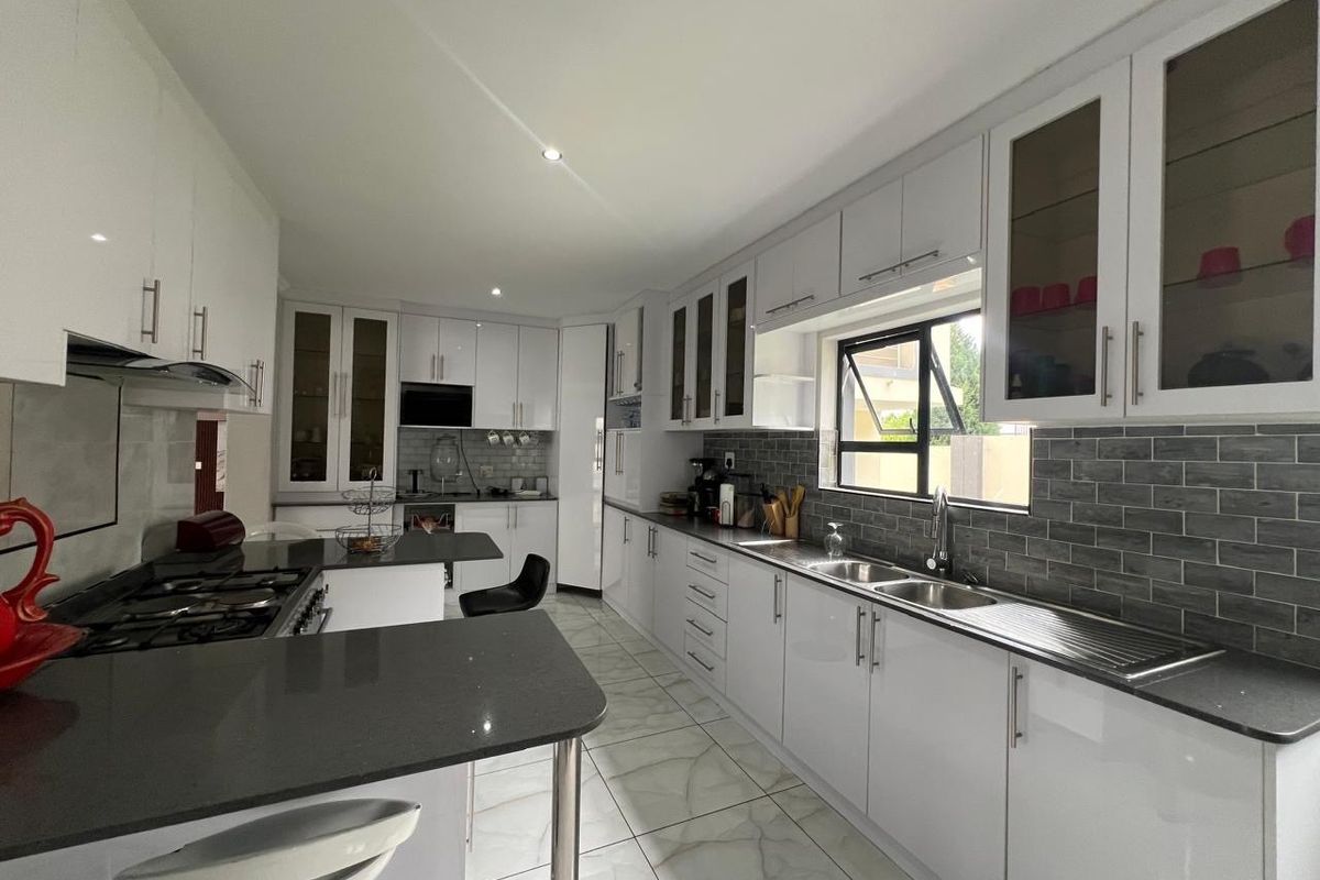 Modern kitchen featuring white cabinetry, stone countertops, a gas hob, integrated appliances, and a stylish subway tile backsplash with ample storage space.