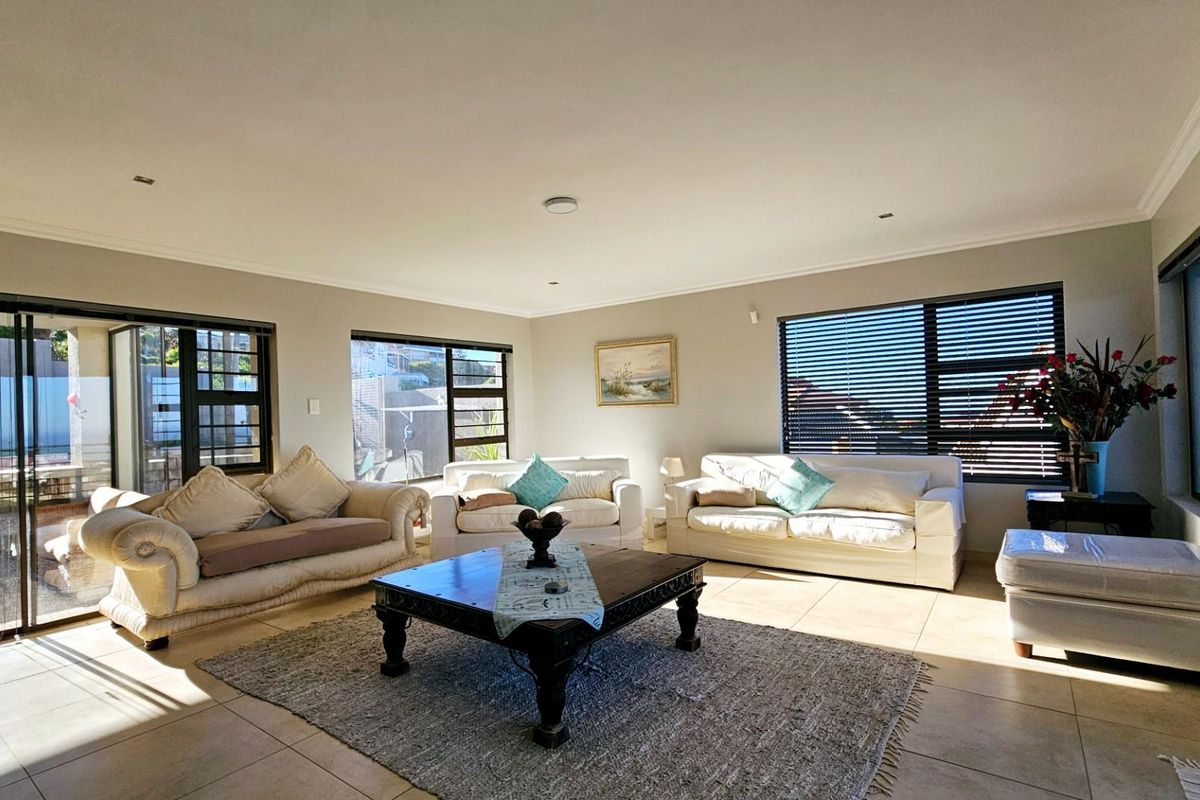 Spacious living room featuring large windows with venetian blinds, tiled flooring, and sliding glass doors leading to an outdoor area.