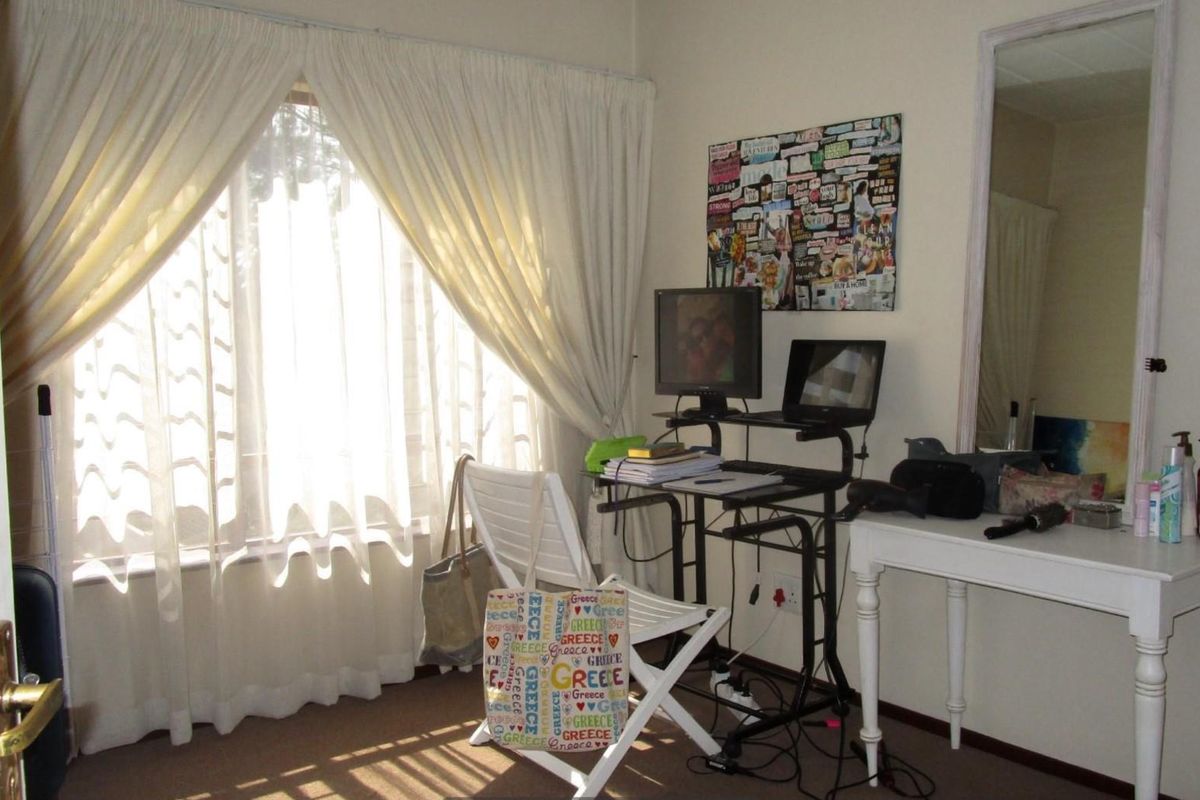 A bedroom featuring carpeted flooring and natural light through a window with installed curtain tracks.