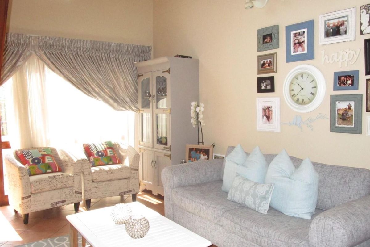A cozy living room featuring tiled flooring, a wooden staircase, and a wall-mounted radiator, offering a comfortable and functional living space.