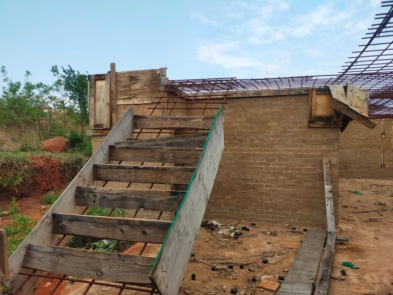 An exterior view of a property under construction, featuring exposed brickwork, steel reinforcement, and temporary wooden formwork for structural elements.