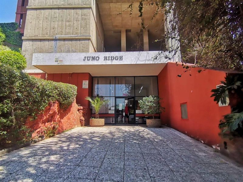 Front entrance view of Juno Ridge apartment building featuring a paved walkway and concrete facade.