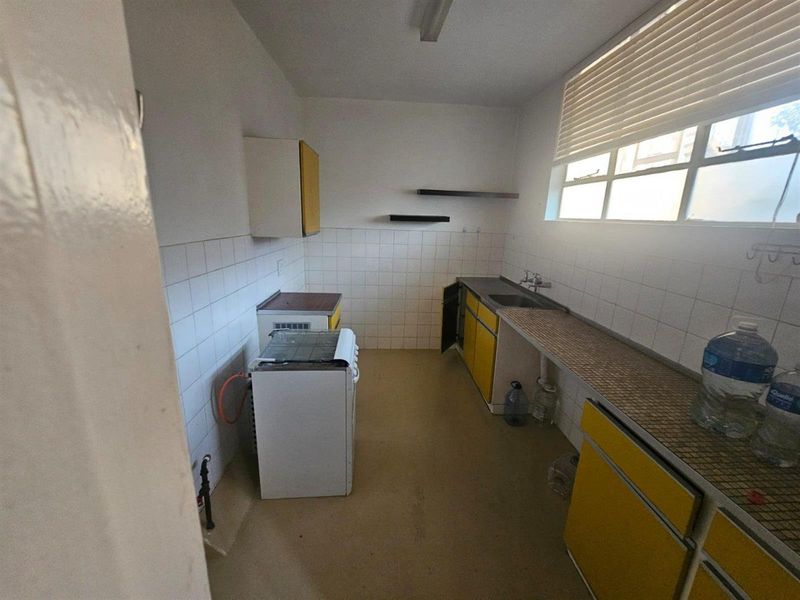 A dated kitchen featuring original cabinetry, tiled backsplash, and a freestanding stove, offering significant potential for a modern renovation.