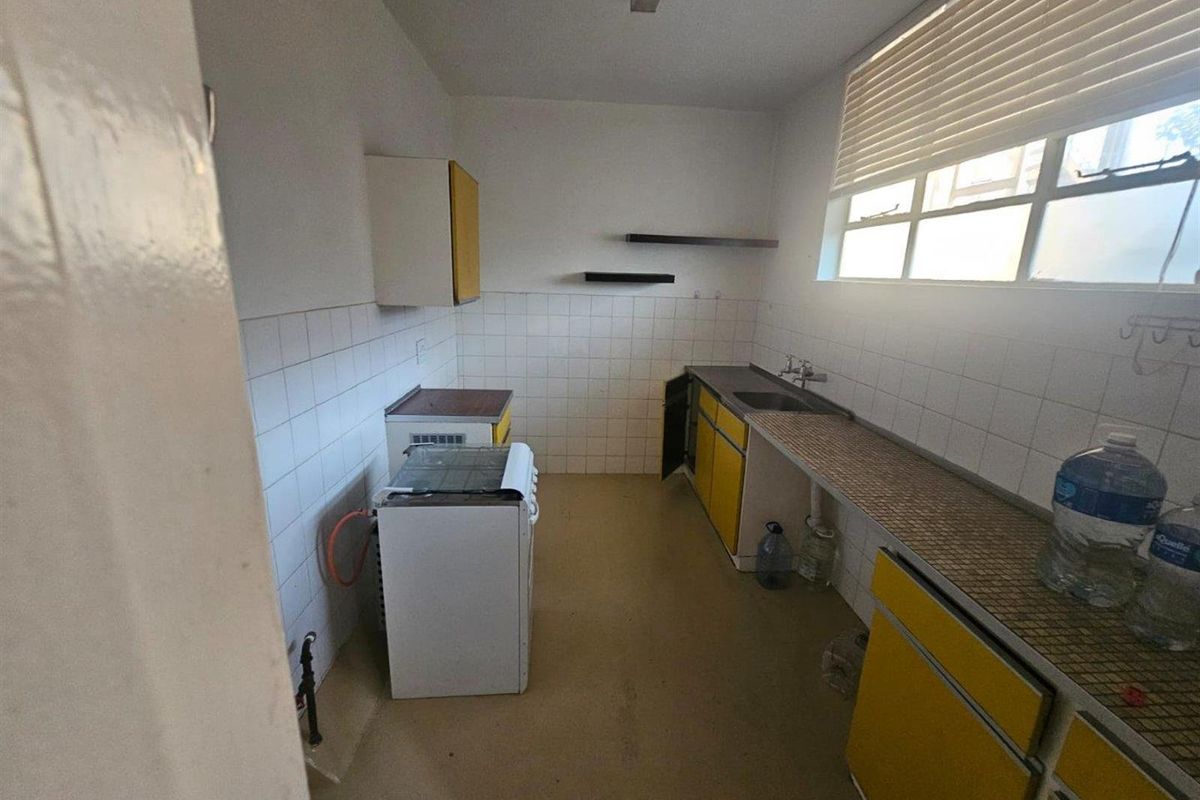 A dated kitchen featuring original cabinetry, tiled backsplash, and a freestanding stove, offering significant potential for a modern renovation.