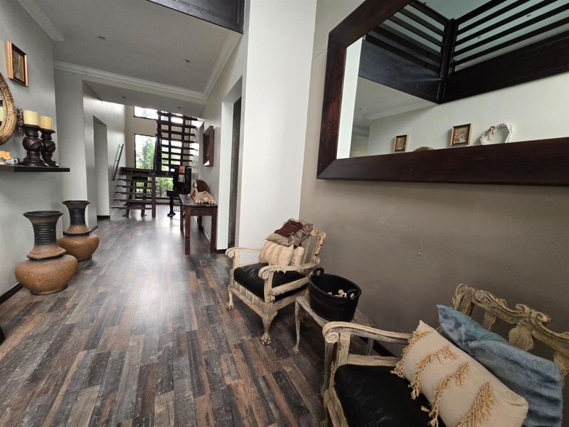 Spacious hallway featuring modern laminate flooring and an open-plan wooden staircase leading to the upper level.