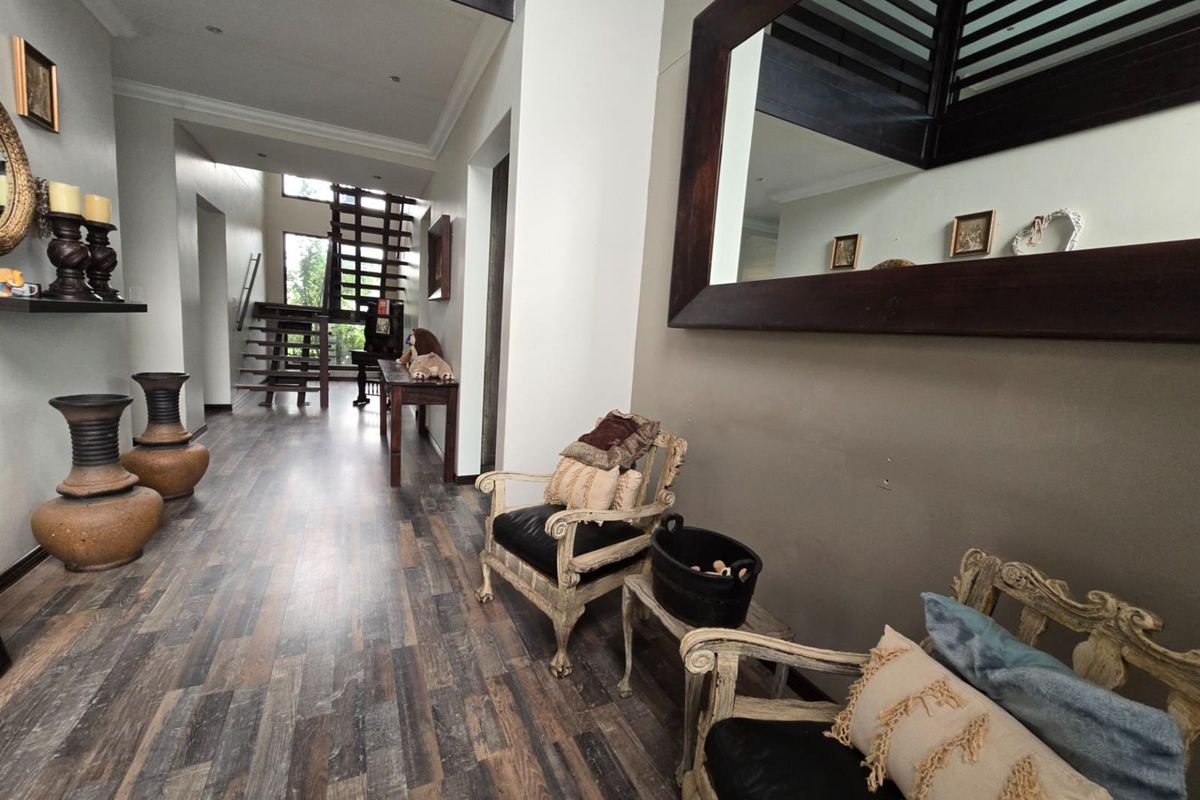 Spacious hallway featuring modern laminate flooring and an open-plan wooden staircase leading to the upper level.