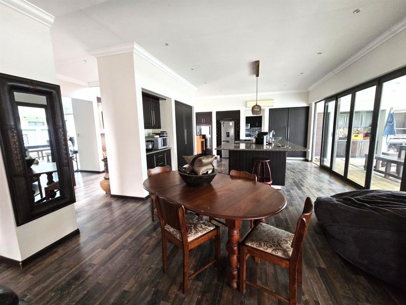 Spacious open-plan living and kitchen area featuring dark cabinetry, a large granite-topped island, and seamless access to the outdoor patio through sliding glass doors.
