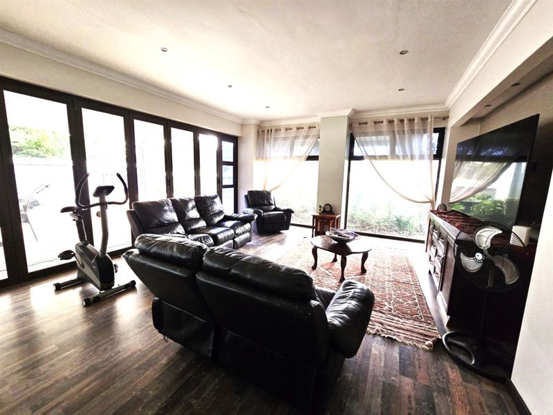 Spacious living room featuring dark laminate flooring, recessed lighting, and large sliding glass doors providing ample natural light and access to the outdoors.