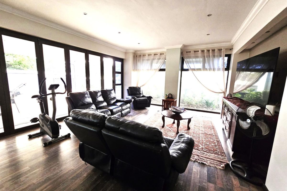 Spacious living room featuring dark laminate flooring, recessed lighting, and large sliding glass doors providing ample natural light and access to the outdoors.