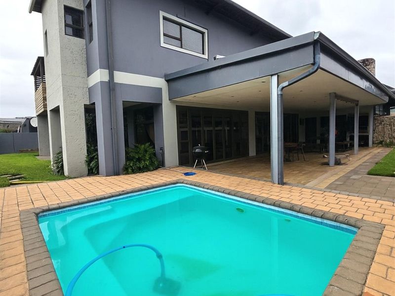 Rear view of the property featuring a swimming pool with paved surround and a spacious covered patio area with recessed lighting.