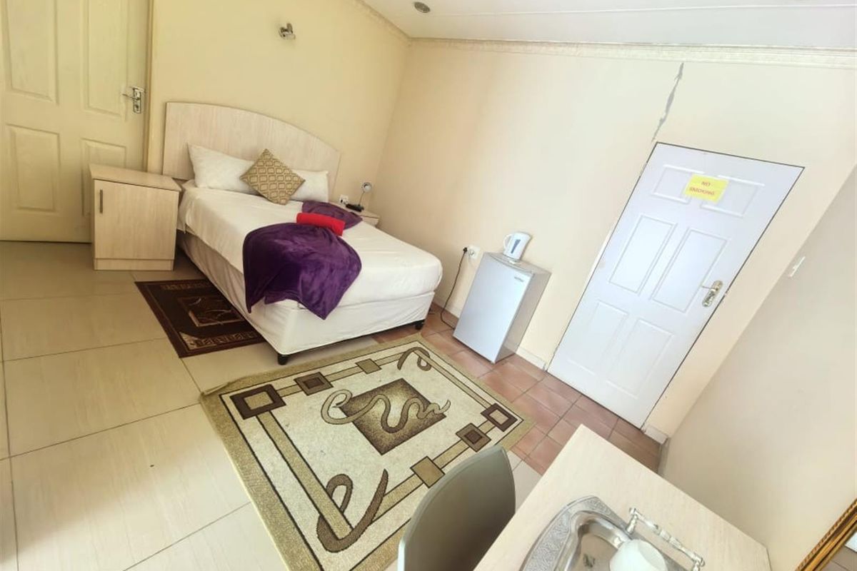 A bedroom featuring tiled flooring, recessed lighting, and a panel door, showing a visible wall crack above the door frame.
