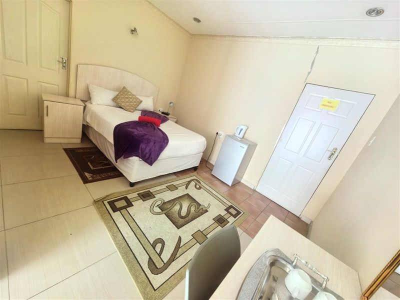 A bedroom featuring tiled flooring, recessed lighting, and a panel door, showing a visible wall crack above the door frame.