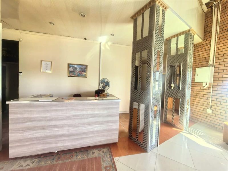 Entrance area featuring a reception desk, decorative mirrored columns, and an exposed brick feature wall with tiled flooring.