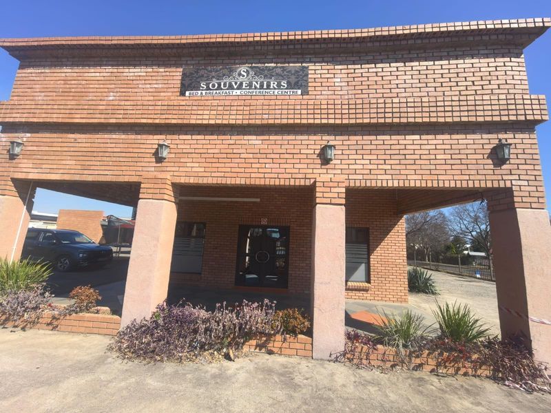 Front elevation of a brick lodge building featuring a covered entrance, masonry pillars, and exterior wall lighting.