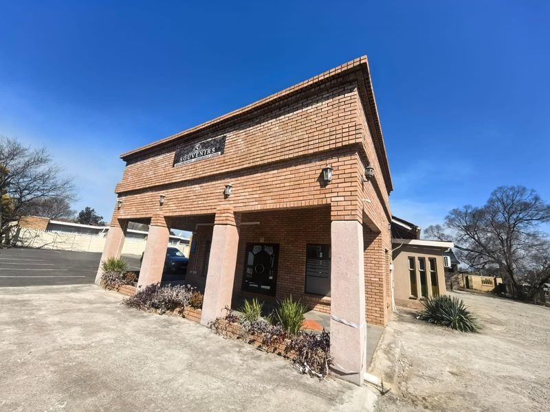 Front elevation of a brick lodge building featuring a covered entrance with concrete pillars and paved driveway access.