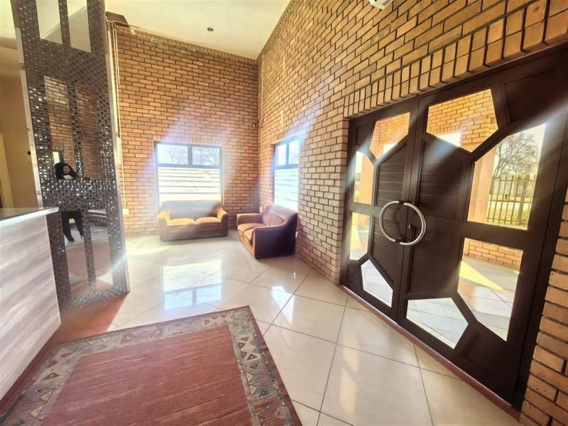 Spacious lodge entrance hall featuring high ceilings, exposed brick walls, and large double doors with decorative glass panels.
