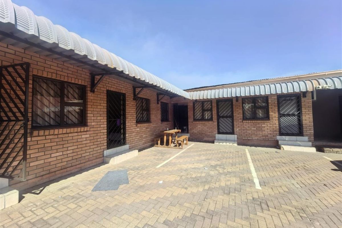 Exterior view of a face brick lodge building featuring a paved courtyard area and multiple secure access points.