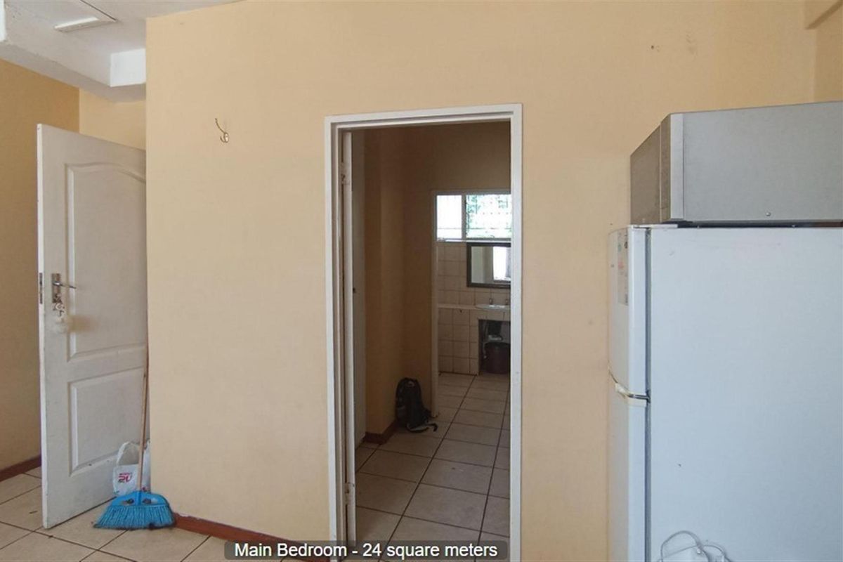 A view of the main bedroom featuring tiled flooring and an adjoining en-suite bathroom area.