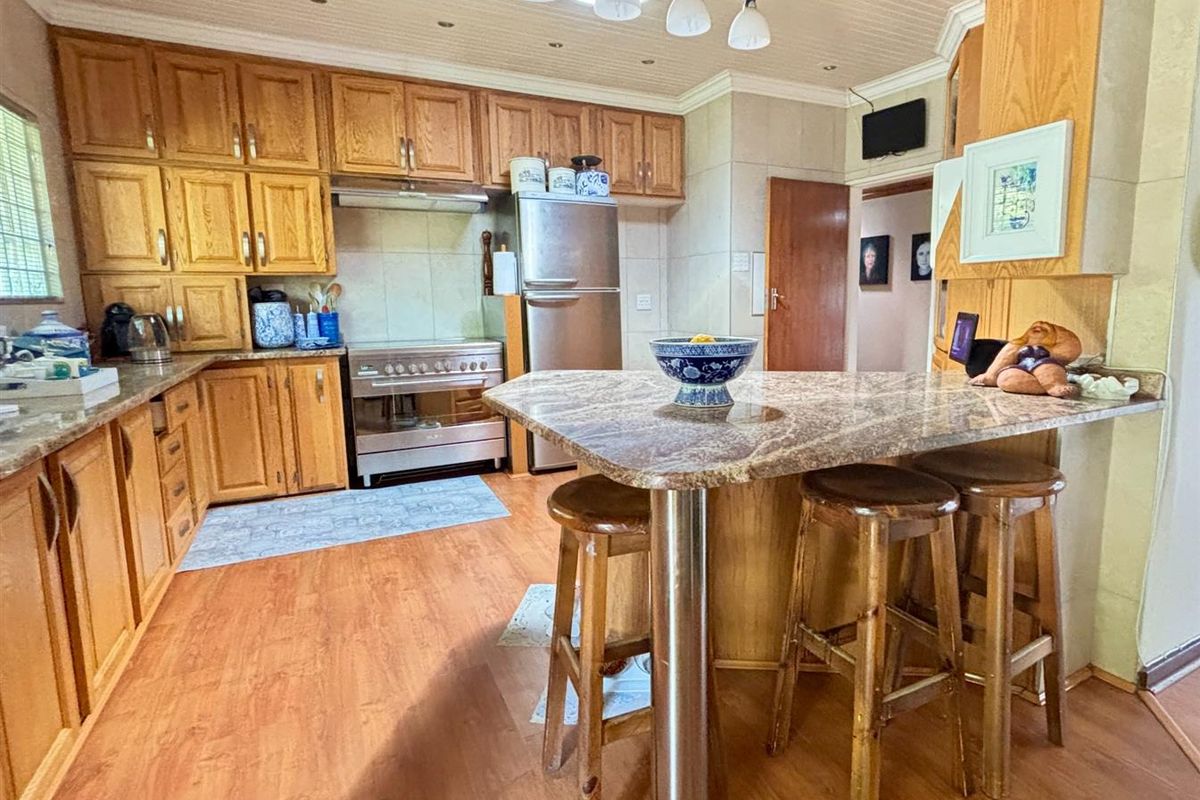 A functional kitchen featuring wooden cabinetry, granite countertops, a breakfast bar, and integrated stainless steel appliances with recessed lighting.