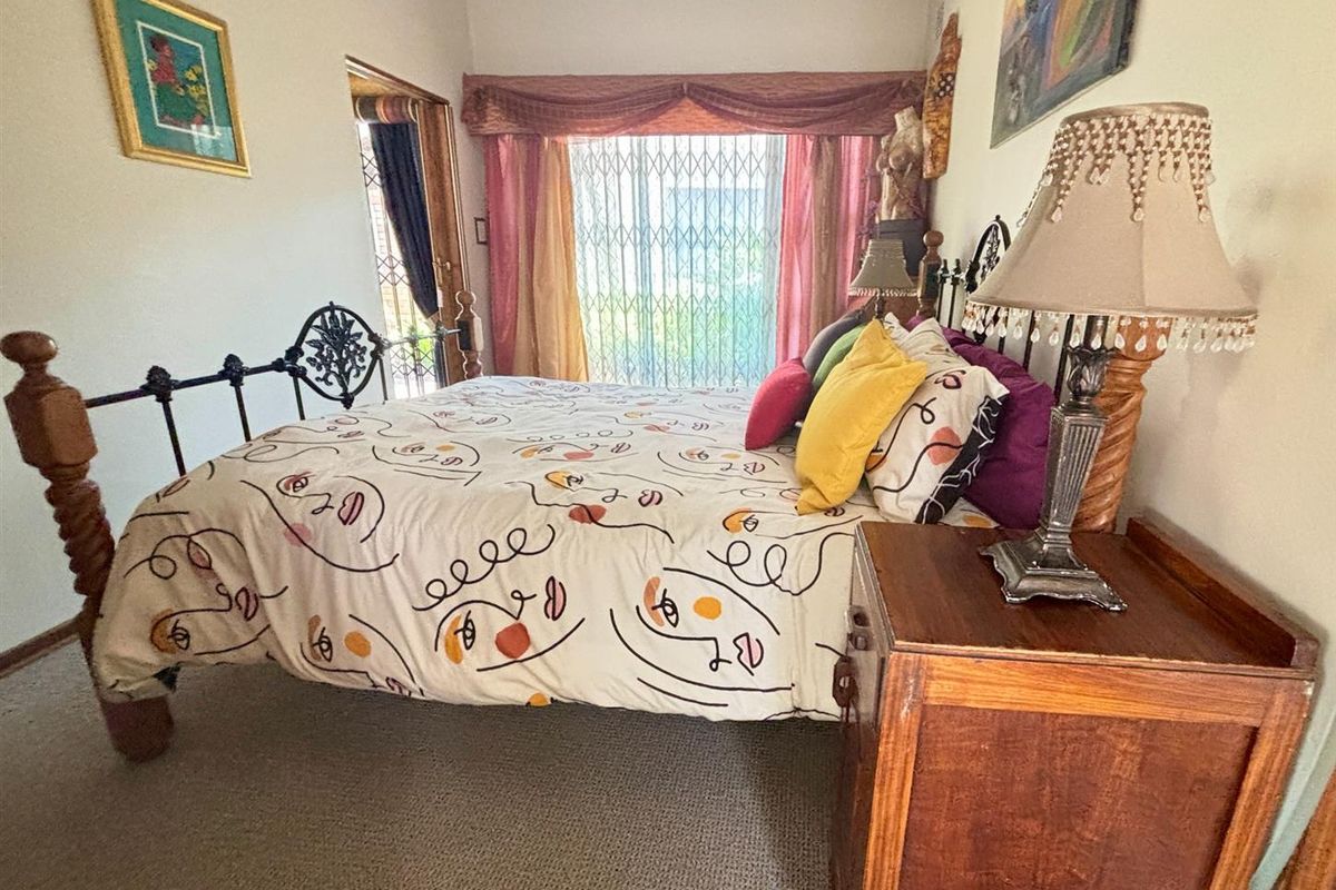 A bedroom featuring carpeted flooring, decorative cornice, and a security gate over the window.