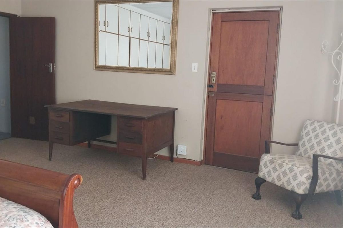 A bedroom featuring carpeted flooring, a solid timber door, and built-in storage cupboards.