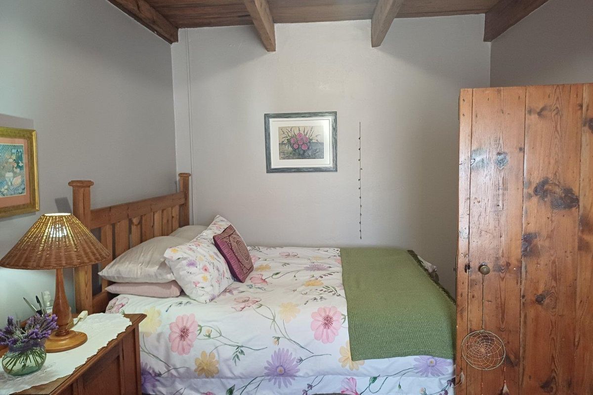 A cozy bedroom featuring exposed timber ceiling beams and a built-in wooden door.