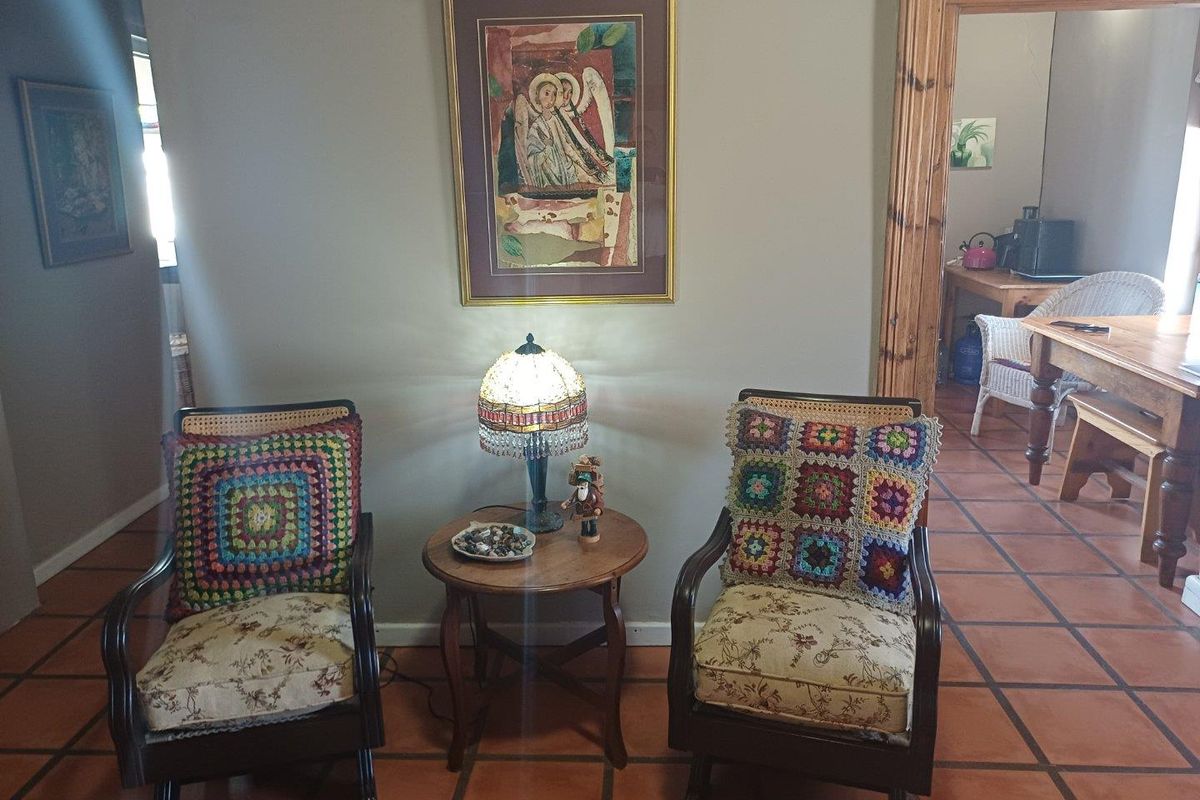 A cozy seating area featuring terracotta floor tiles and a wooden door frame leading to an adjacent dining space.