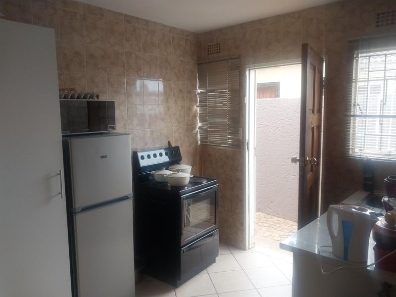 A functional kitchen featuring tiled walls, tiled flooring, and a freestanding oven, with direct access to an outdoor area.