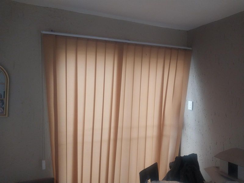 A living area featuring textured walls and vertical blinds covering a large window or sliding door.