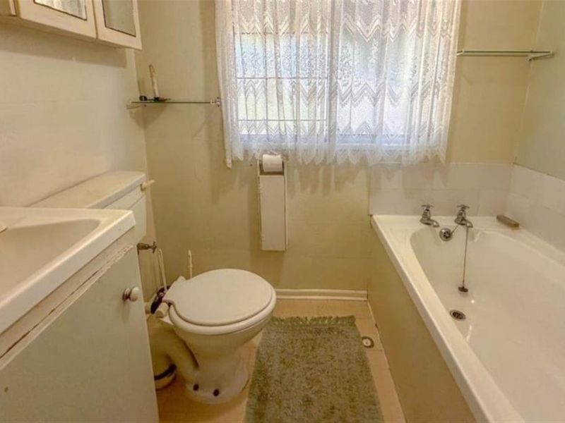 A dated bathroom featuring a standard bathtub, toilet, and vanity unit, offering potential for modernization and cosmetic updates.