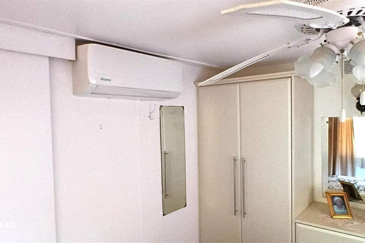 A bedroom featuring a built-in wardrobe, ceiling fan, and wall-mounted air conditioning unit.