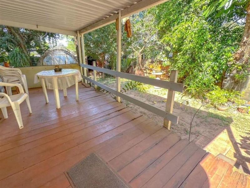 A covered timber patio featuring a wooden balustrade, overlooking a private garden area, providing a functional outdoor space for relaxation.