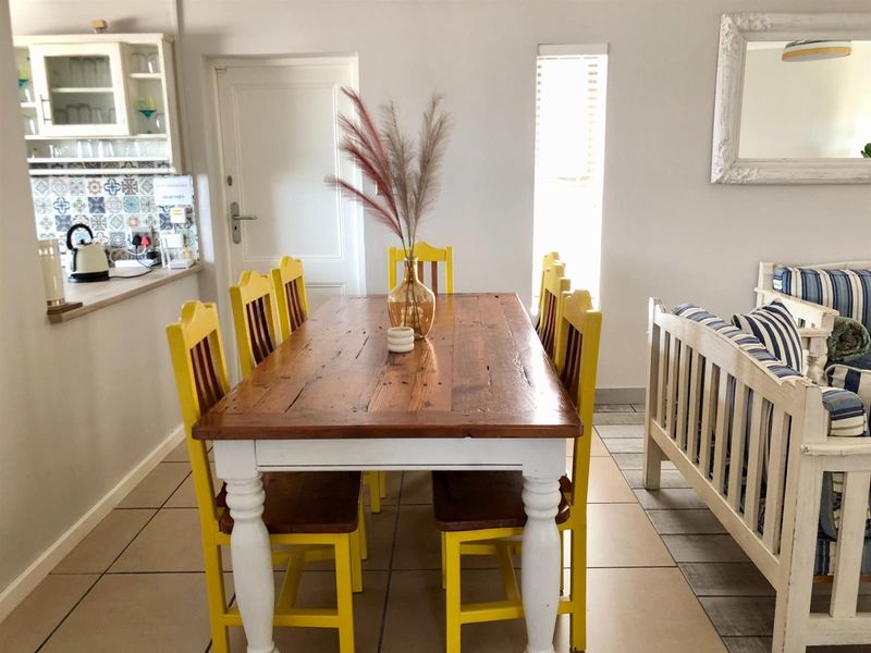 Open plan dining area featuring tiled flooring, adjacent to a kitchen with patterned backsplash tiles and built-in cabinetry.