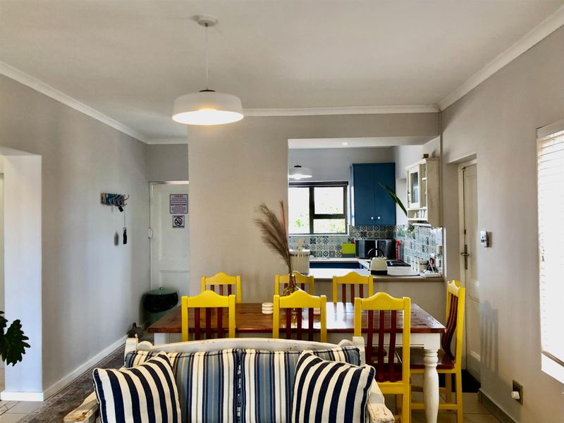 Open plan living and dining area featuring a functional kitchen with blue cabinetry and decorative tiled backsplash.