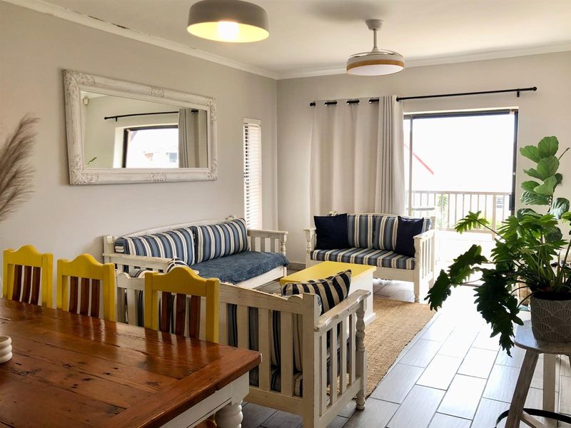 Open-plan living and dining area featuring tiled flooring, ceiling fans, and direct access to a balcony through sliding glass doors.