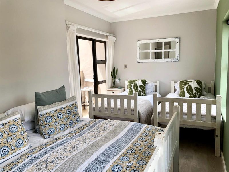 A well-lit bedroom featuring neutral walls, laminate flooring, and a sliding glass door providing access to an outdoor patio area.