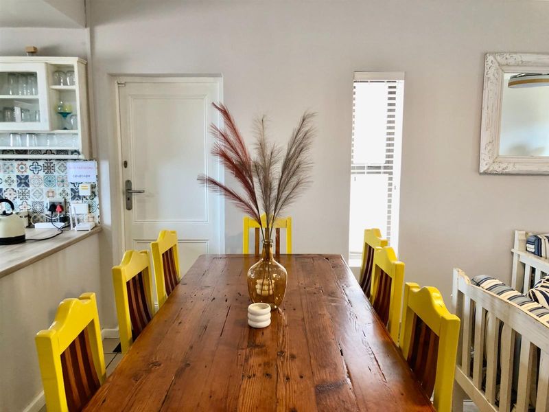 A dining area featuring a wooden table, adjacent to a kitchen with patterned tile backsplash and built-in cabinetry.