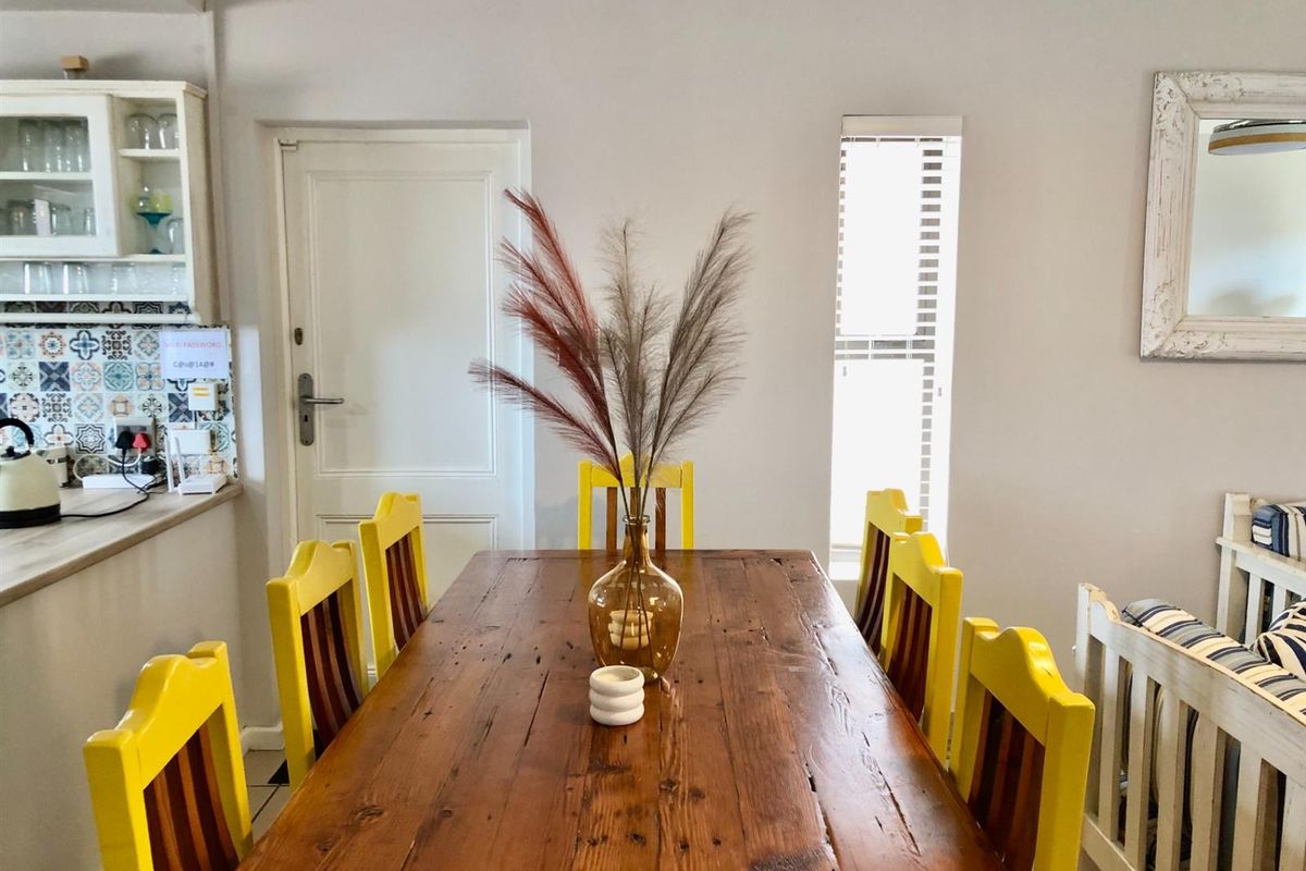 A dining area featuring a wooden table, adjacent to a kitchen with patterned tile backsplash and built-in cabinetry.