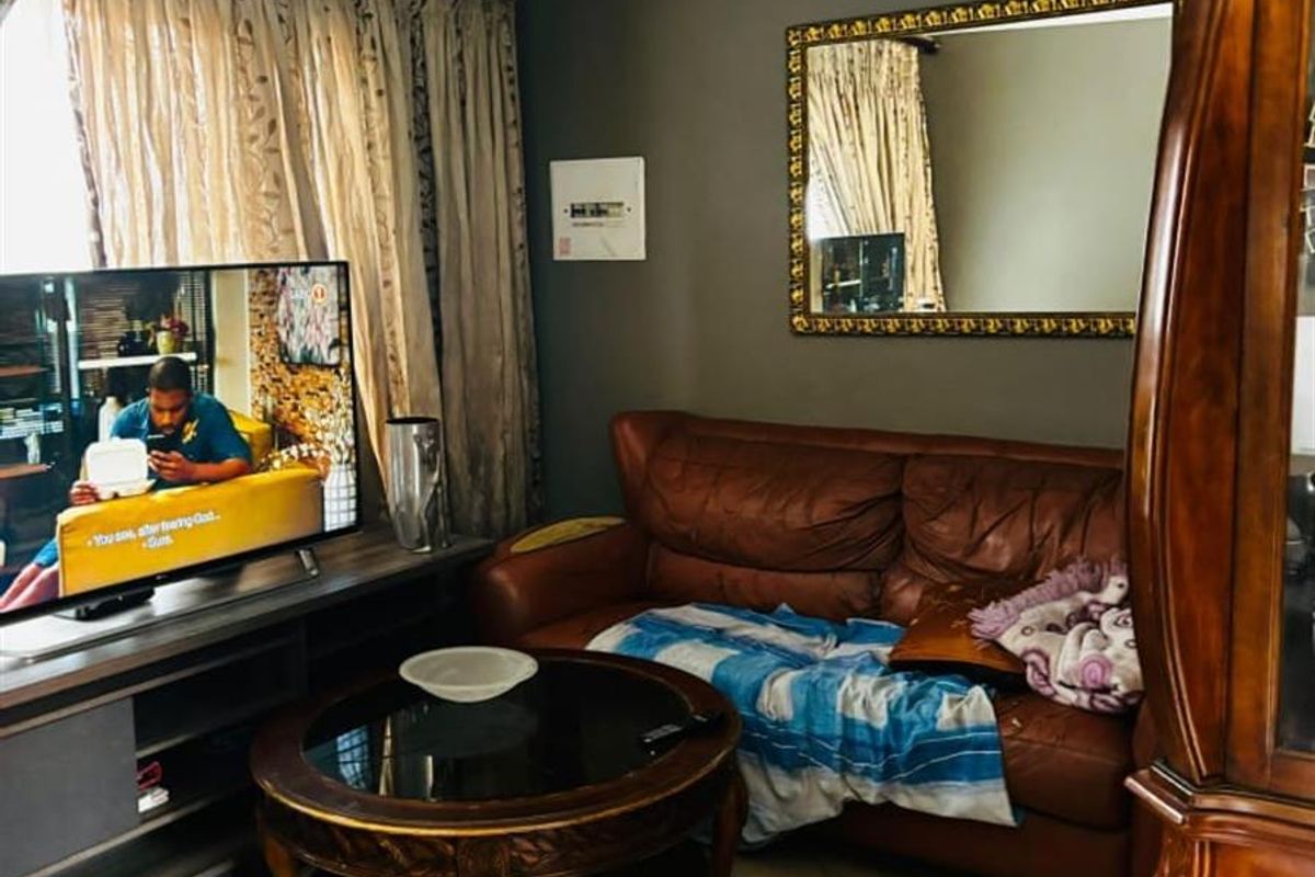 A cozy living room featuring tiled flooring, dark grey walls, and a large window with curtains, providing a comfortable space for relaxation.