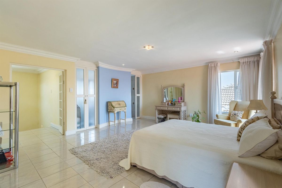 Spacious bedroom featuring tiled flooring, built-in cupboards, and large windows allowing for natural light.