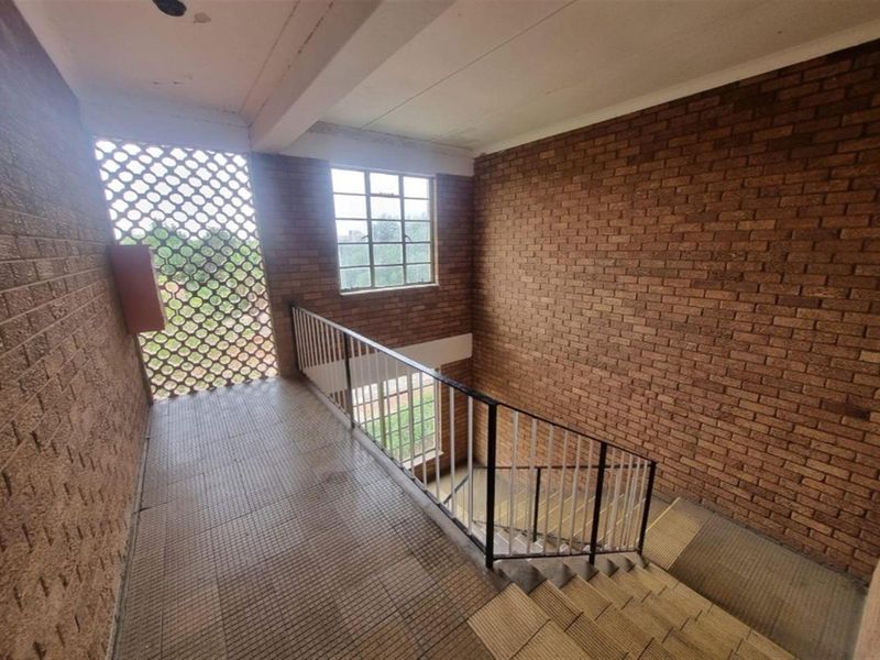 A functional stairwell area featuring exposed brick walls, tiled flooring, and a decorative breeze block screen, providing access between levels.