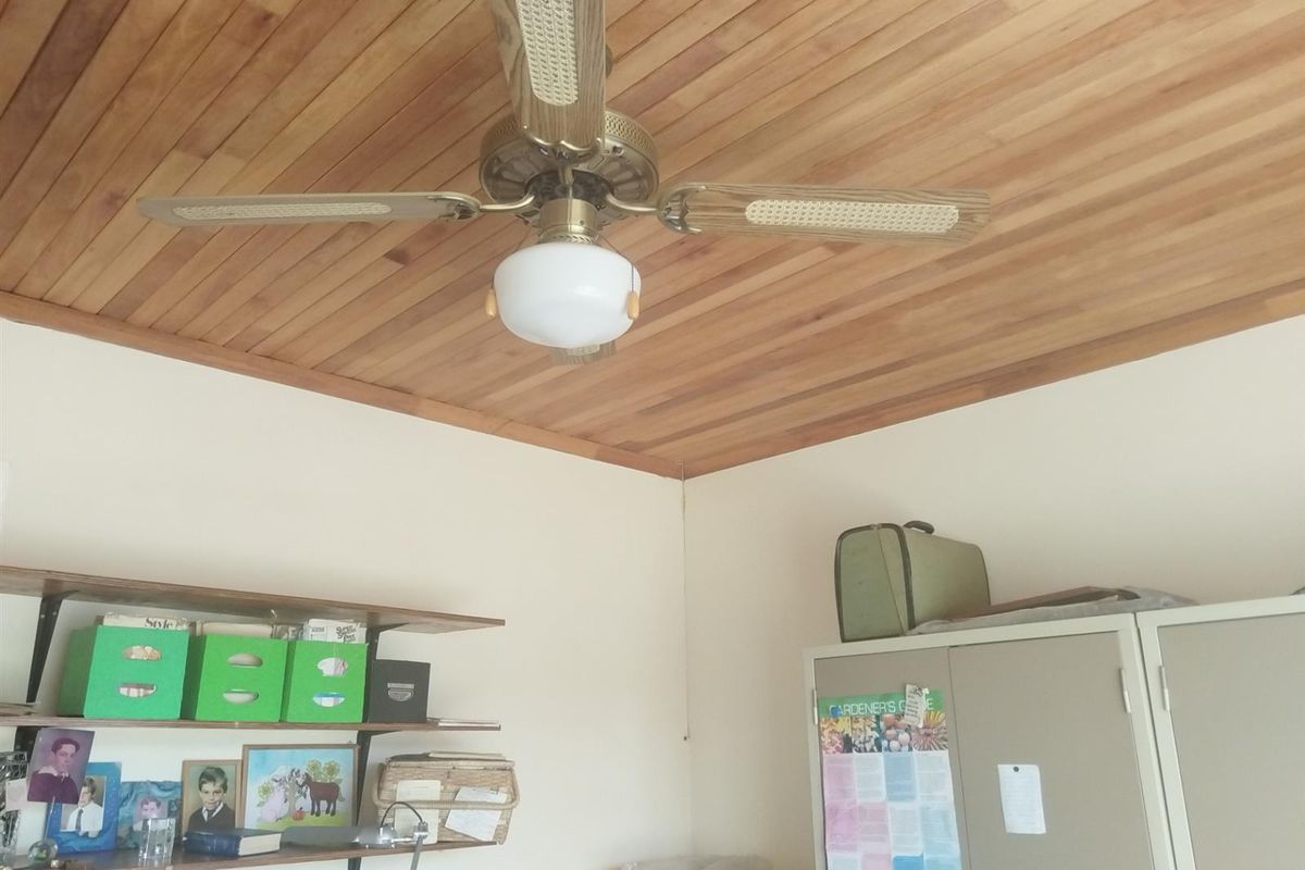 A bedroom featuring a timber-clad ceiling and a central ceiling fan, providing a rustic aesthetic.
