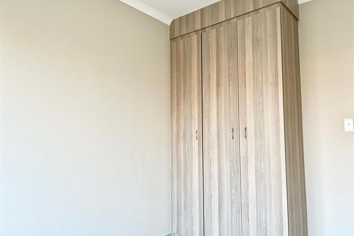 A bedroom featuring built-in wooden cupboards with a modern finish and neutral wall tones.