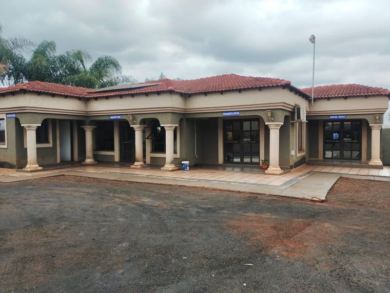 Front elevation of a single-story office building featuring a covered patio, multiple glass entrance doors, and a tiled roof.