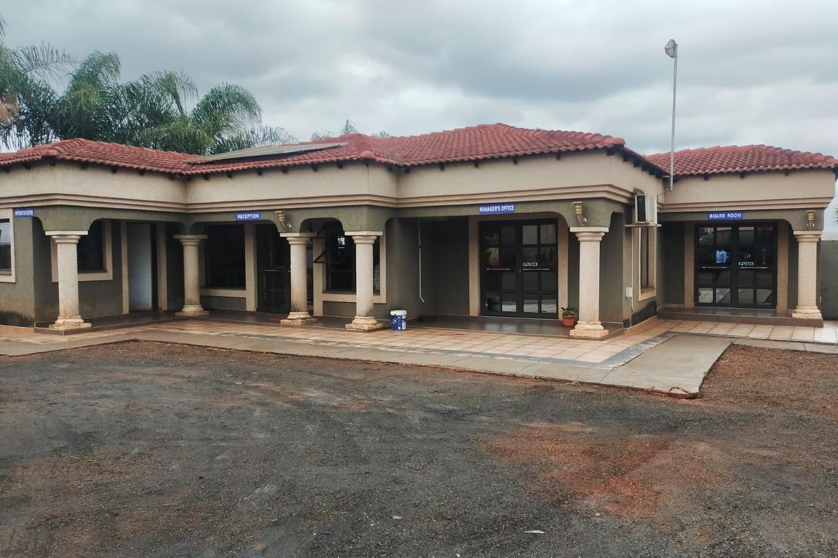 Front elevation of a single-story office building featuring a covered patio, multiple glass entrance doors, and a tiled roof.